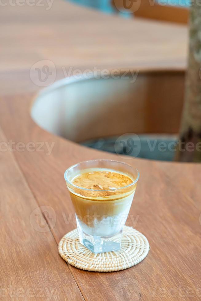 copo de café sujo ou leite frio coberto com uma dose de café expresso quente em uma cafeteria foto