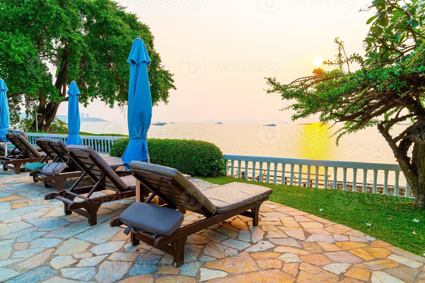 cadeiras de praia ou camas de piscina com guarda-sóis ao redor da piscina na hora do pôr do sol foto