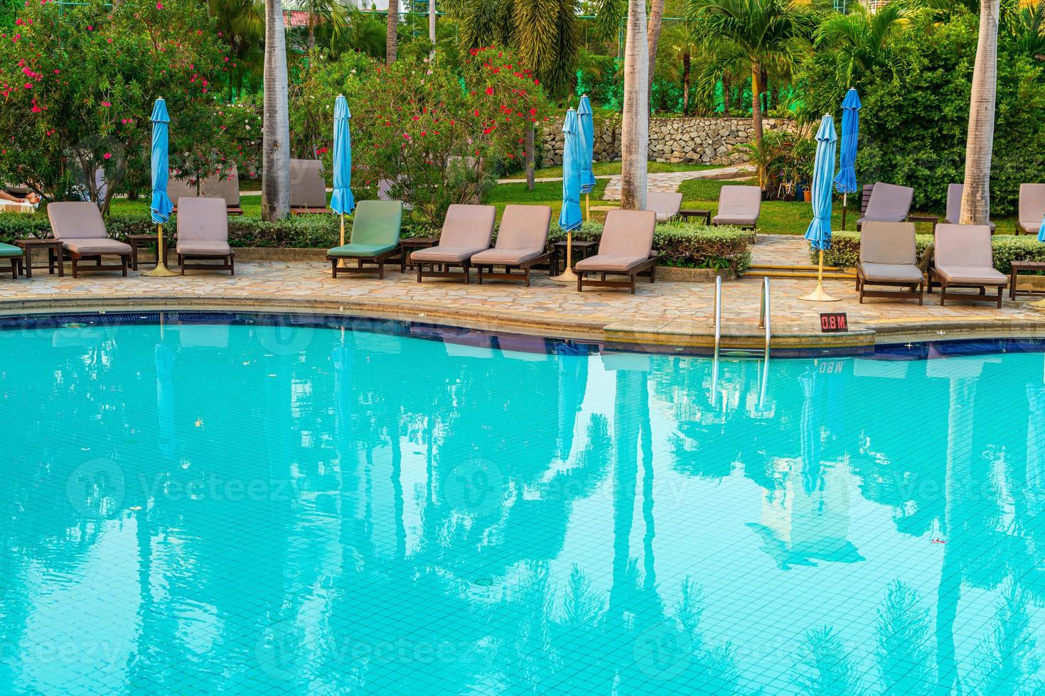 cadeiras de praia ou camas de piscina com guarda-sóis ao redor da piscina na hora do pôr do sol foto