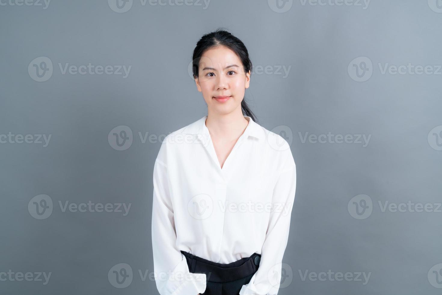 Mulher asiática feliz com carinha feliz em uma camisa branca em fundo cinza foto