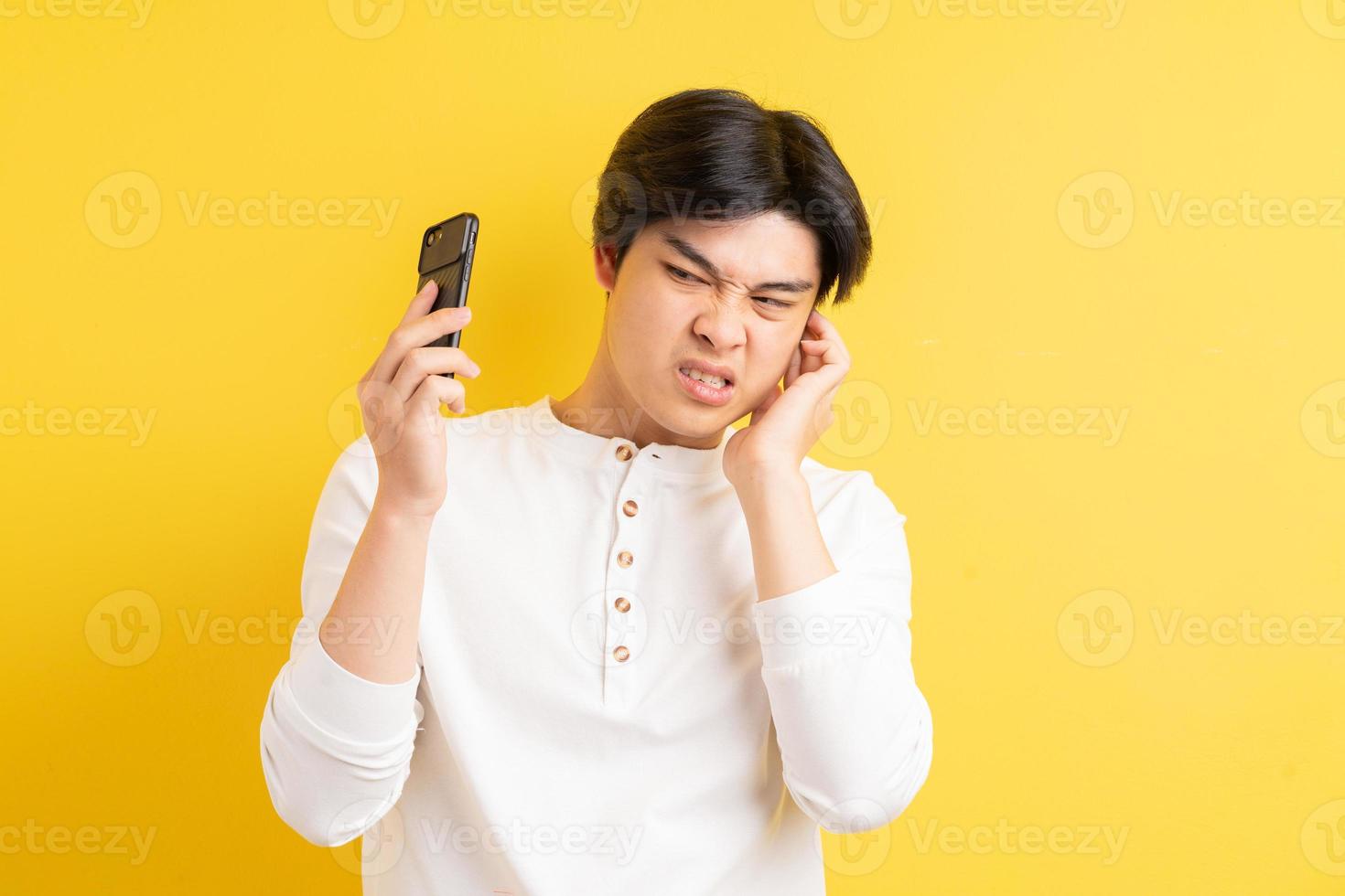 homem asiático sendo gritado em seu ouvido enquanto falava ao telefone foto