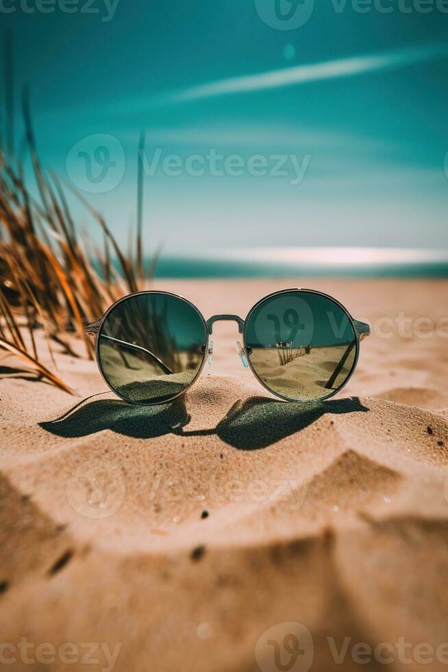 uma par do oculos de sol sentado em topo do uma arenoso de praia foto