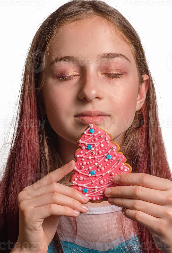 menina e pão de mel de Natal na forma de uma árvore de Natal rosa. foto