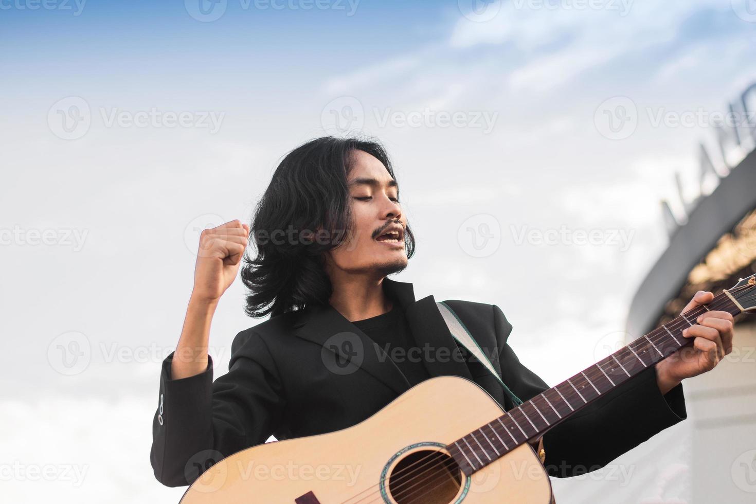 homem canta música e toca guitarra ao ar livre foto