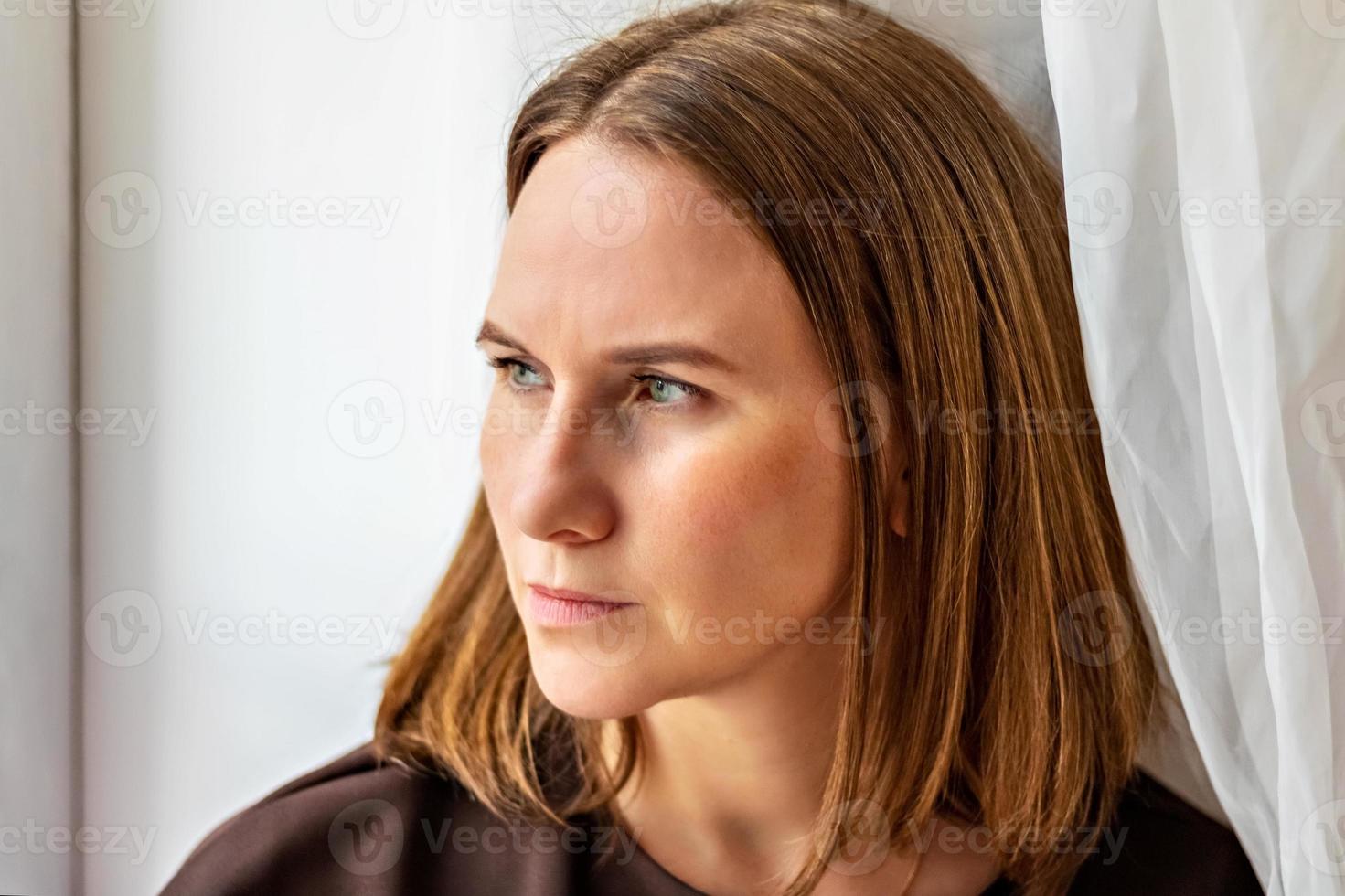 retrato de uma jovem mulher pensativa, sentada perto da janela. fechar-se foto