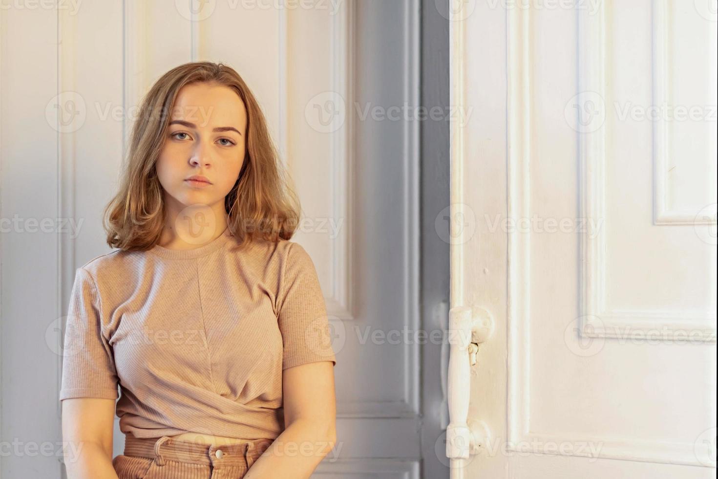 uma linda jovem elegante está sentada na porta do quarto dela. adolescente. tristeza foto