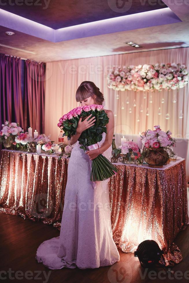 noiva feliz com um grande buquê de rosas. bela jovem sorridente noiva contém grande buquê com rosas cor de rosa. casamento em tons rosados e verdes. a cerimônia de casamento. foto