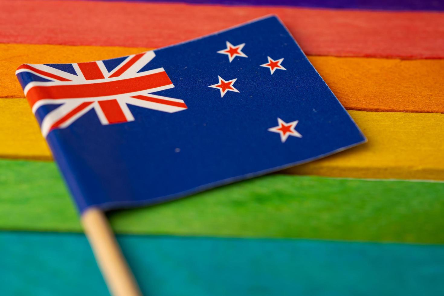 bandeira da nova zelândia no fundo do arco-íris símbolo da bandeira do movimento social do mês do orgulho gay LGBT A bandeira do arco-íris é um símbolo de lésbicas, gays, bissexuais, transgêneros, direitos humanos, tolerância e paz. foto