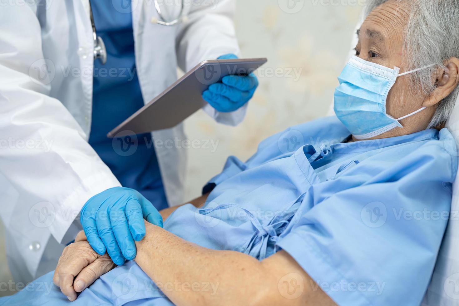 médico asiático usando protetor facial e terno novo normal para verificar o paciente protege a segurança infecção covid-19 surto de coronavírus na enfermaria de quarentena do hospital. foto