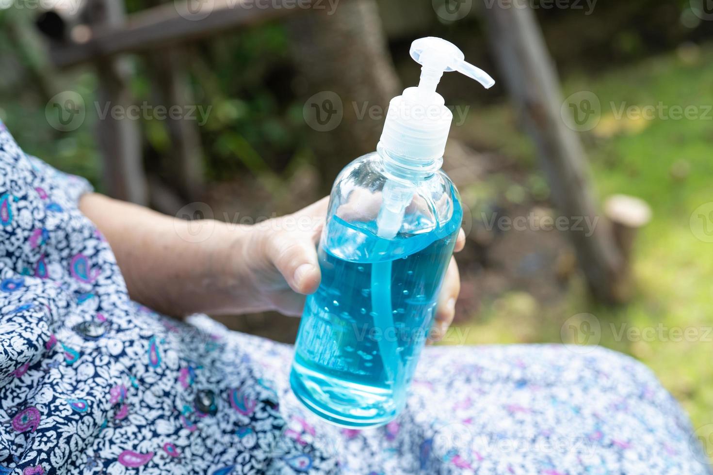 paciente asiático sênior ou idosa senhora segurando gel desinfetante de álcool azul para proteger a infecção de segurança e matar o coronavírus covid-19, bactérias e germes. foto