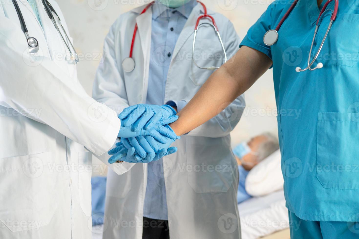 A equipe do médico asiático junta as mãos como uma equipe para motivar o novo normal para tratar a infecção por coronavírus covid-19 na enfermaria do hospital. foto