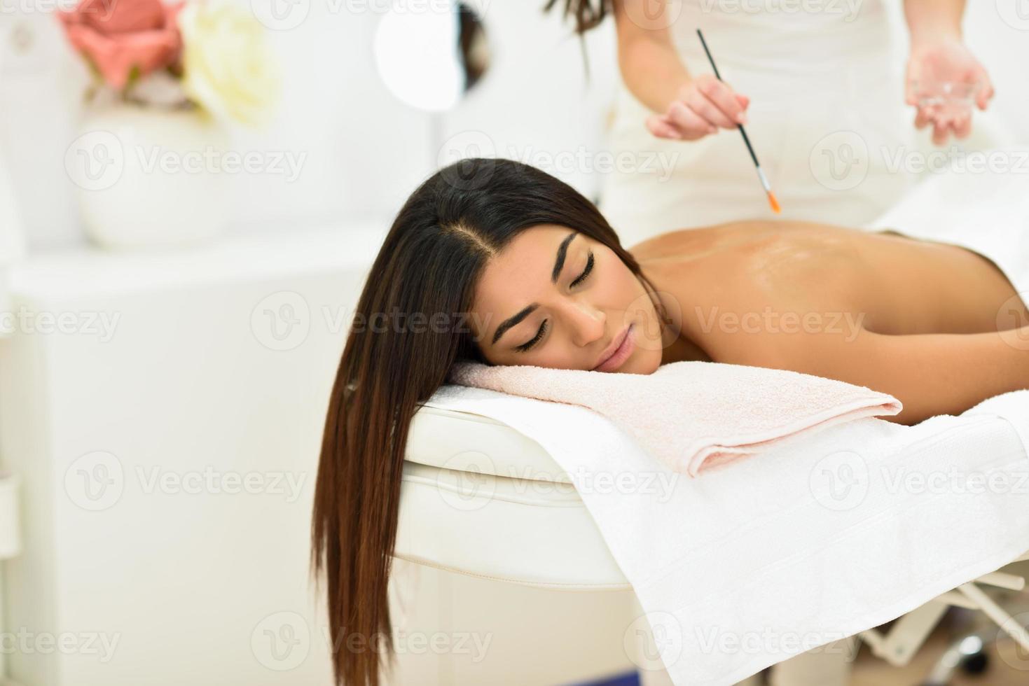 mulher árabe em spa de beleza e bem-estar fazendo massagem com aromaterapia foto