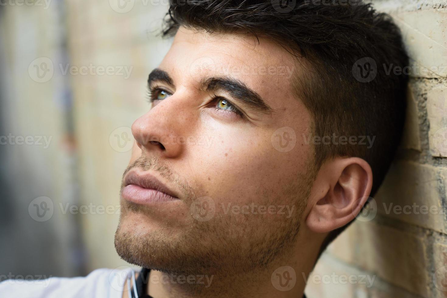 jovem bonito com olhos azuis, posando perto de uma parede foto