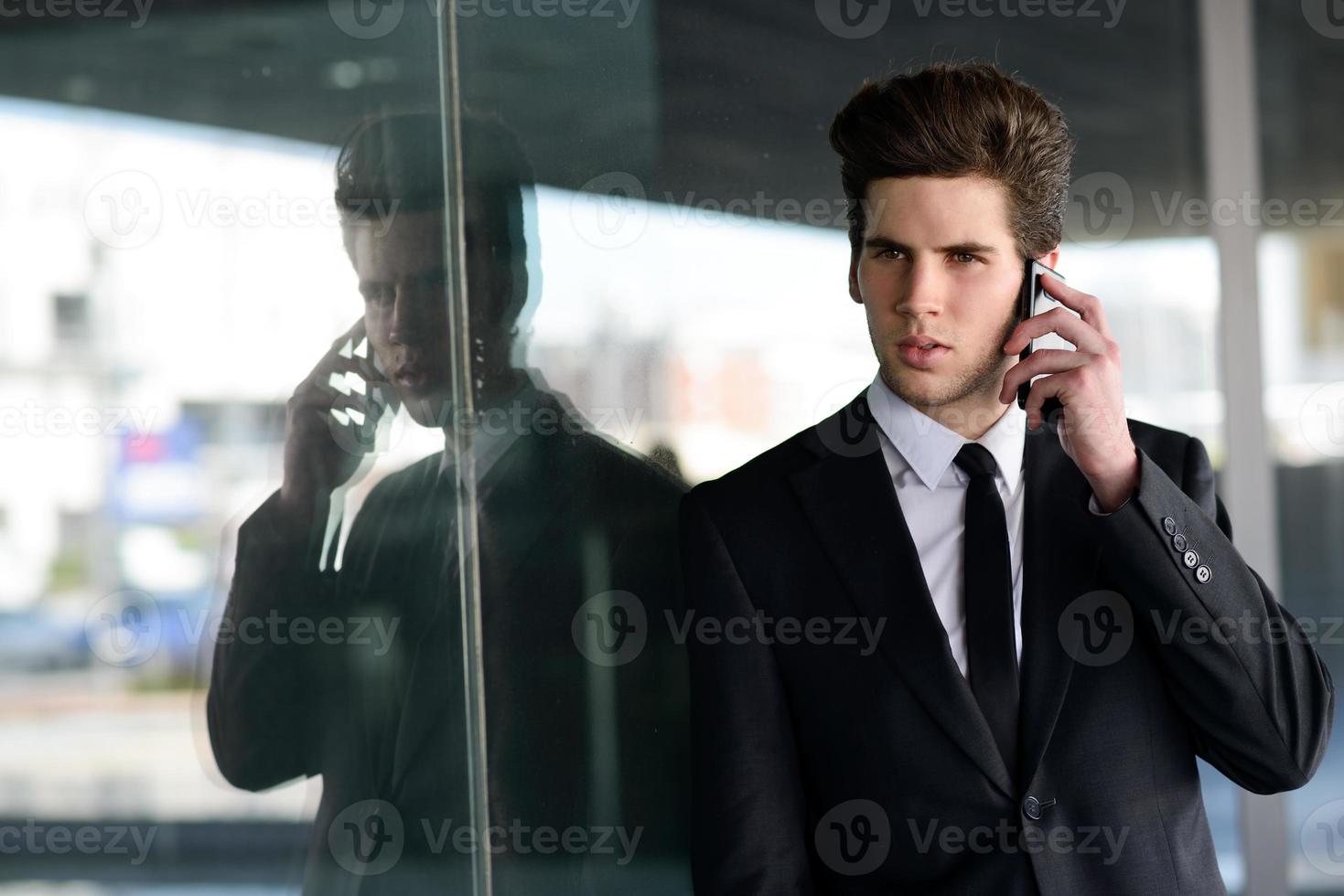 atraente jovem empresário ao telefone em um prédio de escritórios foto