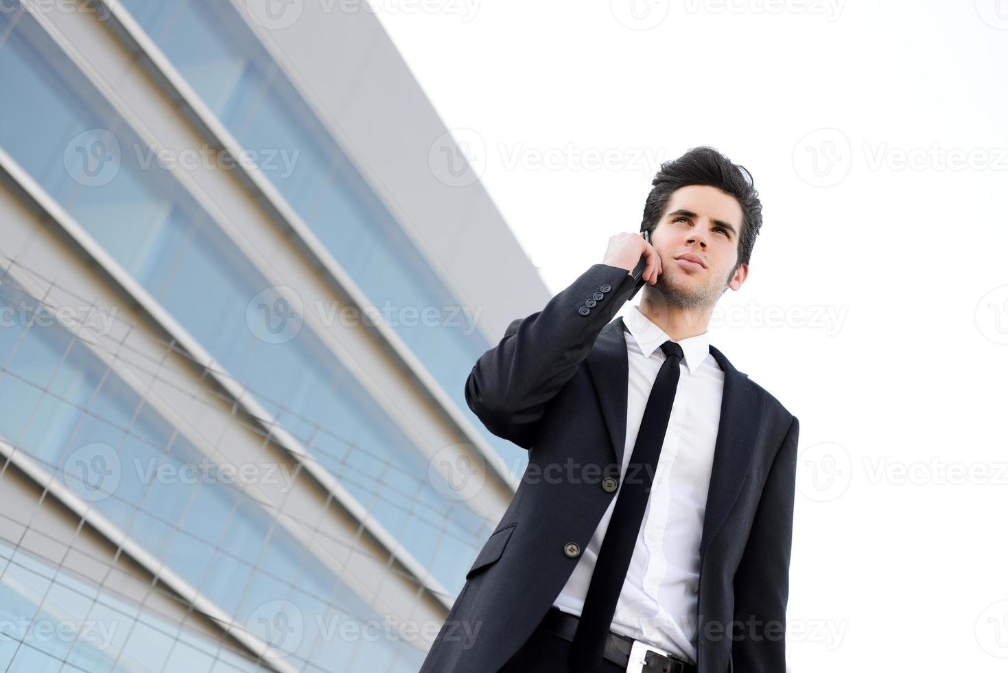 atraente jovem empresário ao telefone em um prédio de escritórios foto