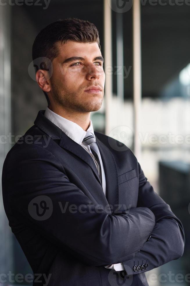 jovem empresário perto de um prédio de escritórios vestindo terno preto foto