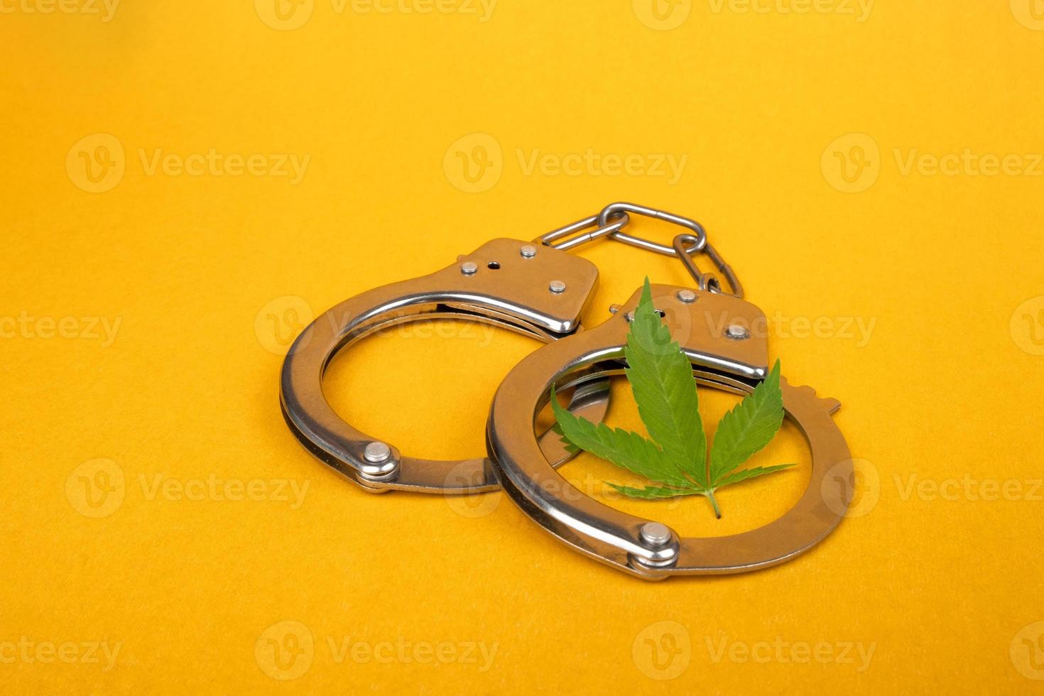 algemas e uma folha de cannabis em um fundo amarelo, prisão por distribuição ilegal de maconha foto