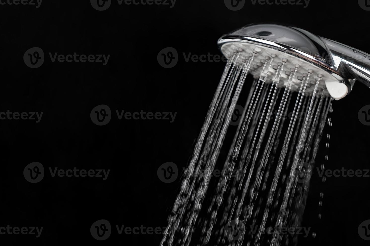 espalhando respingos de água por um chuveiro em um fundo escuro foto