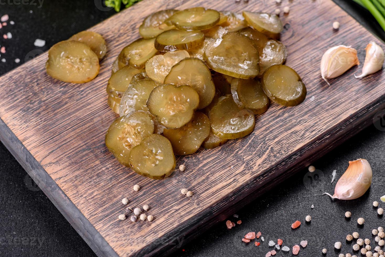 saboroso pepino em conserva picante salgado cortado com anéis em uma tábua de madeira foto