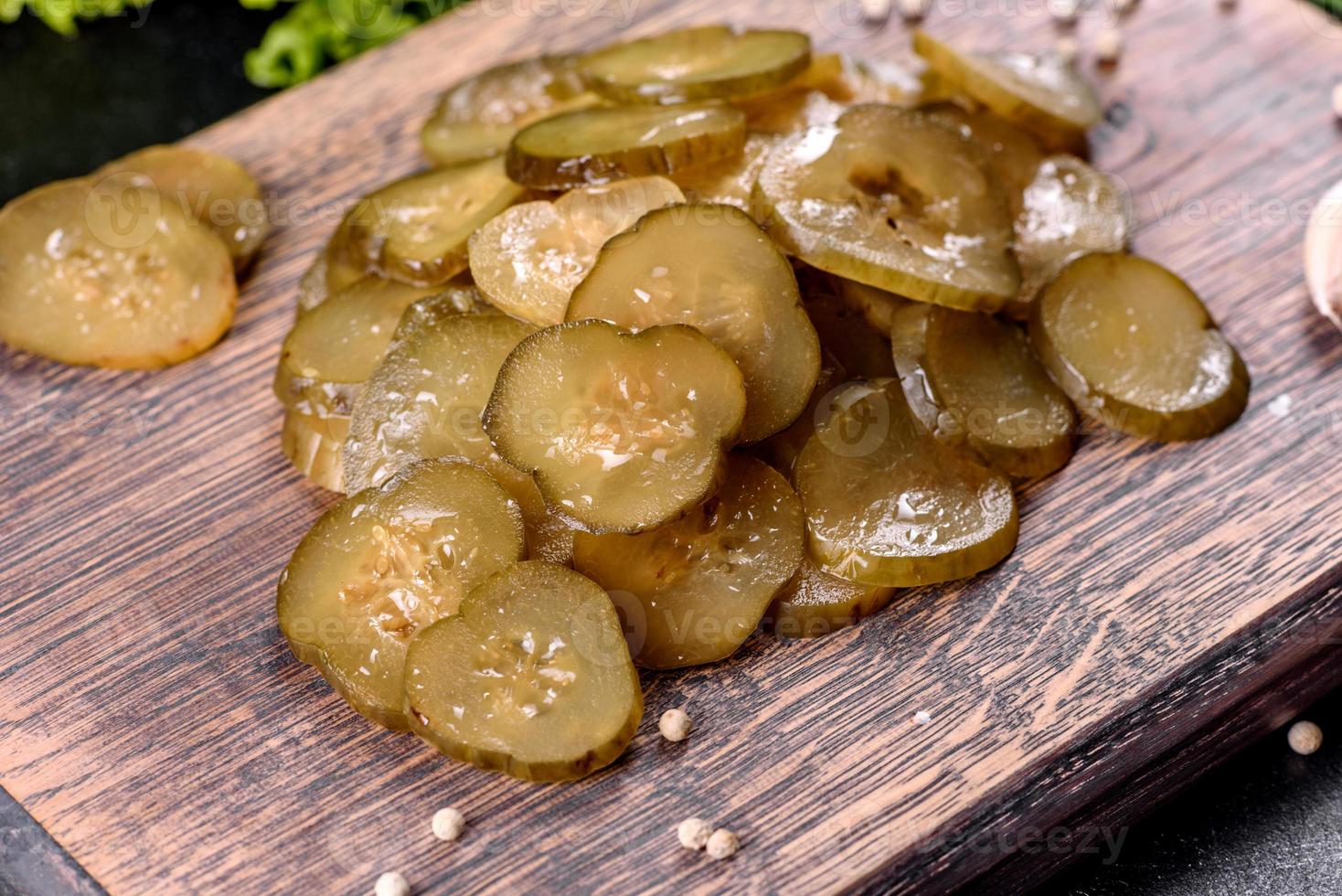 saboroso pepino em conserva picante salgado cortado com anéis em uma tábua de madeira foto