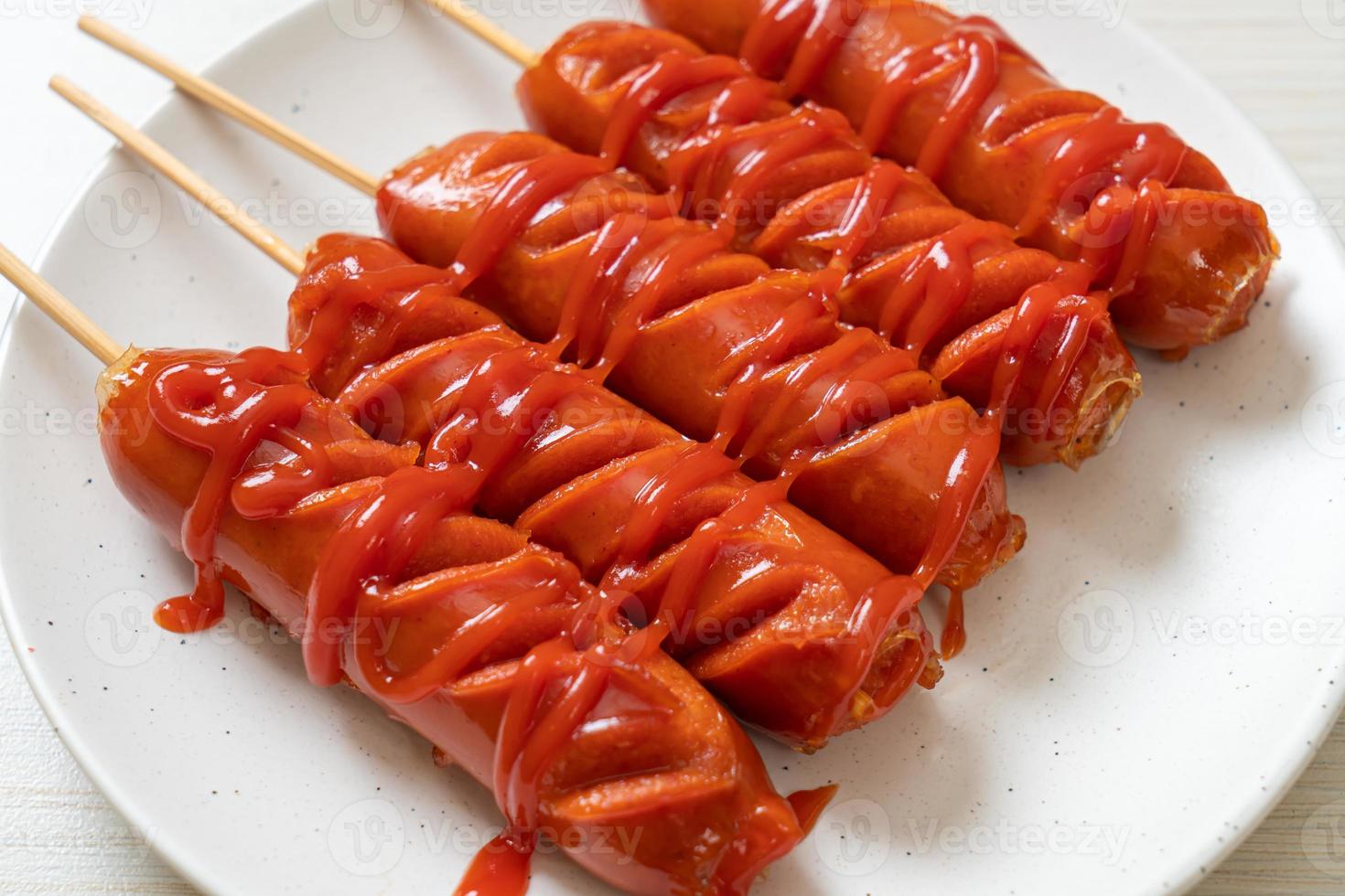 espeto de linguiça frita com ketchup em um prato branco foto