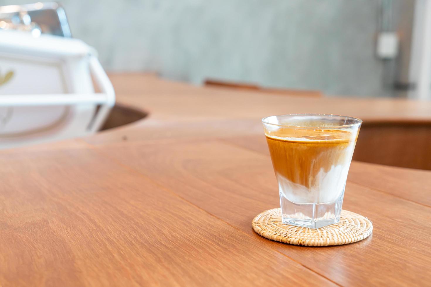 copo de café sujo ou leite frio coberto com uma dose de café expresso quente em uma cafeteria foto