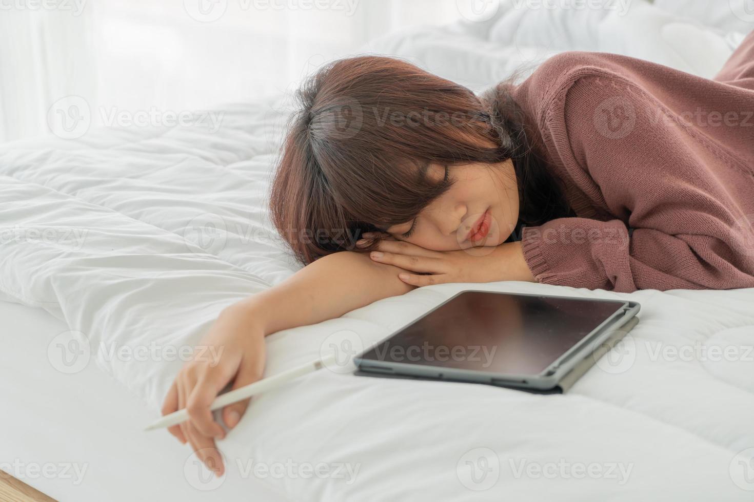 linda mulher asiática trabalhando com tablet na cama foto