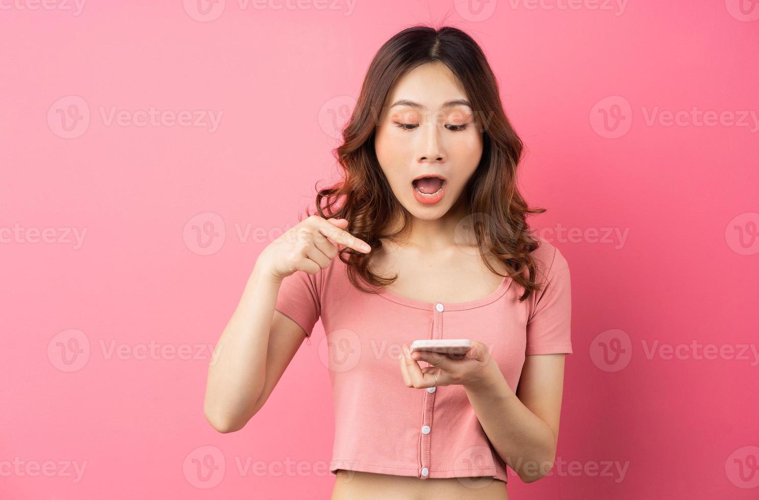 jovem mulher asiática usando o telefone em fundo rosa foto