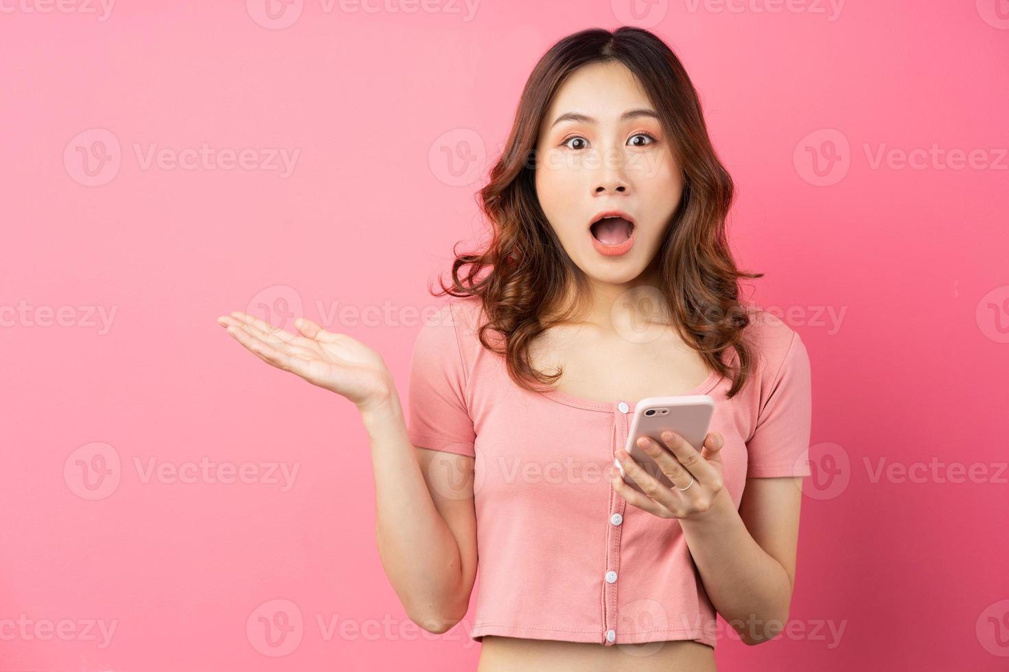 jovem mulher asiática usando o telefone em fundo rosa foto