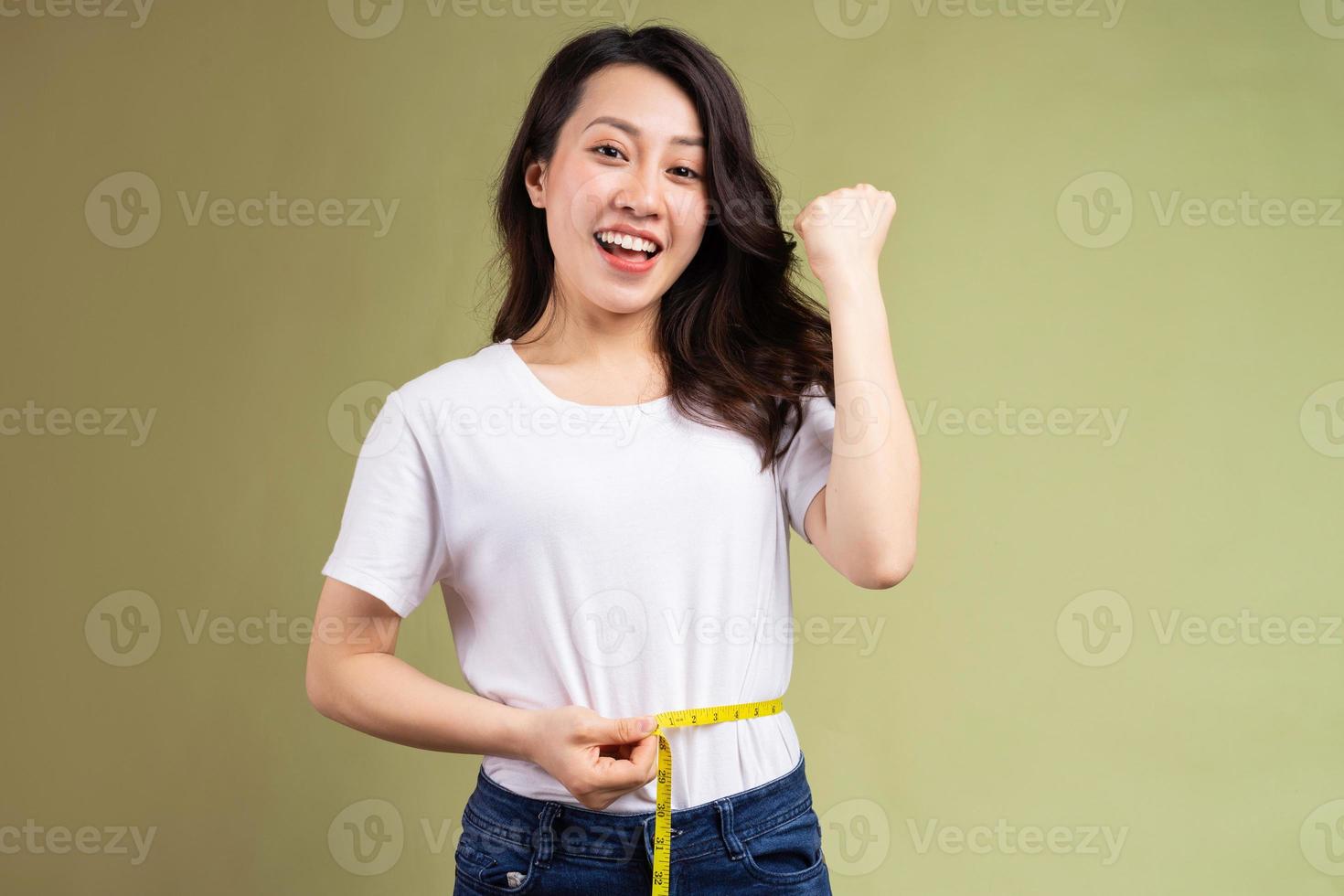 jovem asiática segurando feliz a fita métrica depois de perder peso foto