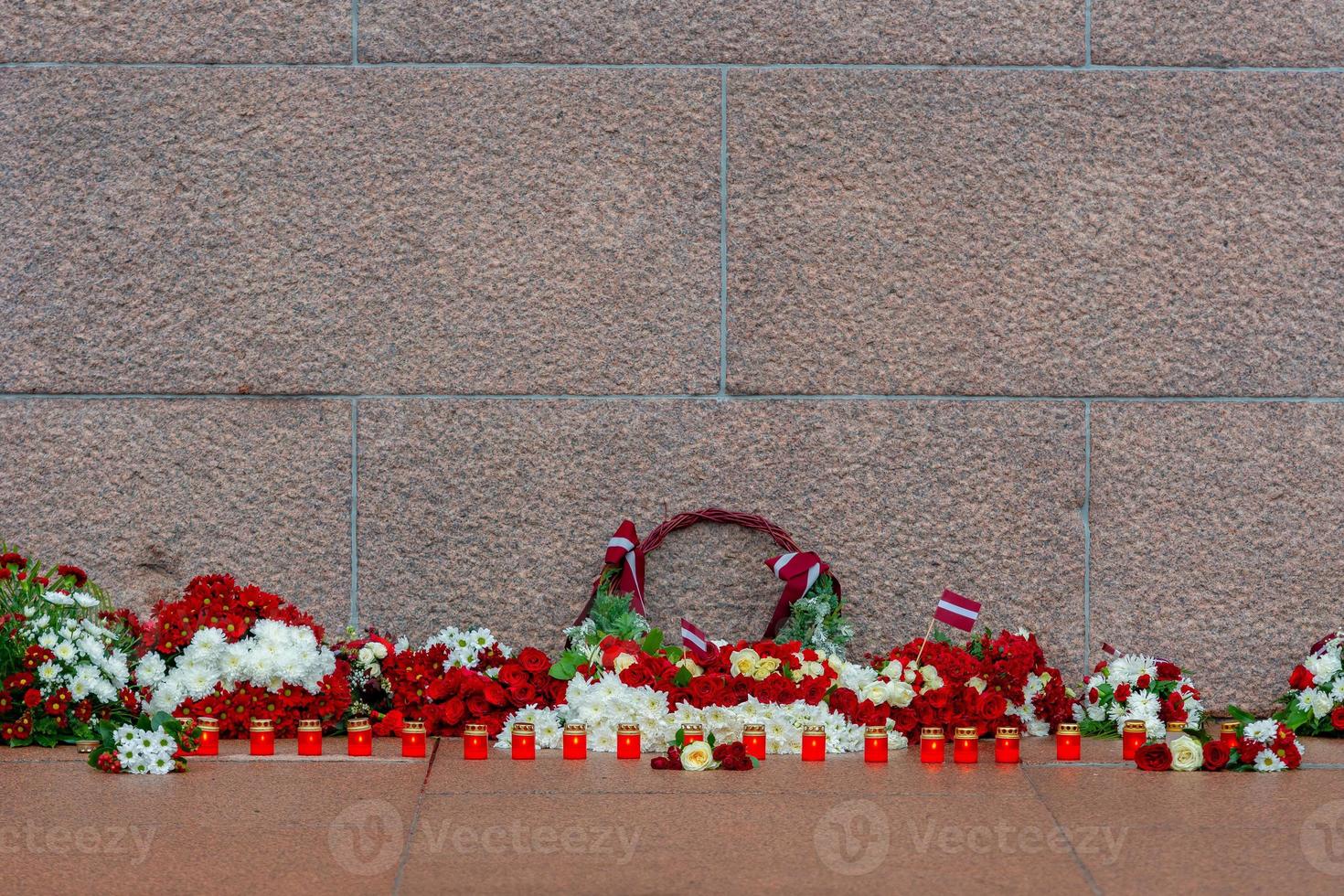 letônia 100 anos. composições de flores vermelhas e brancas no monumento da liberdade na cidade de riga, letônia foto