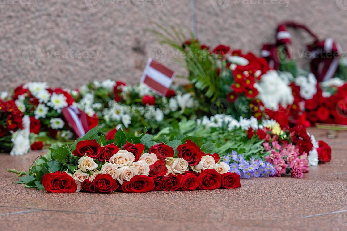 letônia 100 anos. composições de flores vermelhas e brancas no monumento da liberdade na cidade de riga, letônia foto