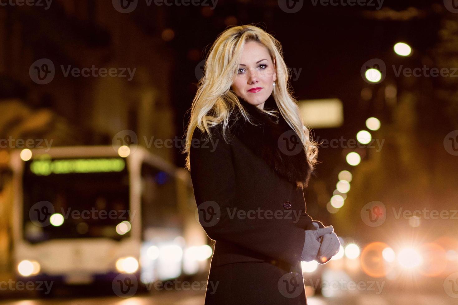 linda mulher loira nas luzes do carro na cidade à noite. foto