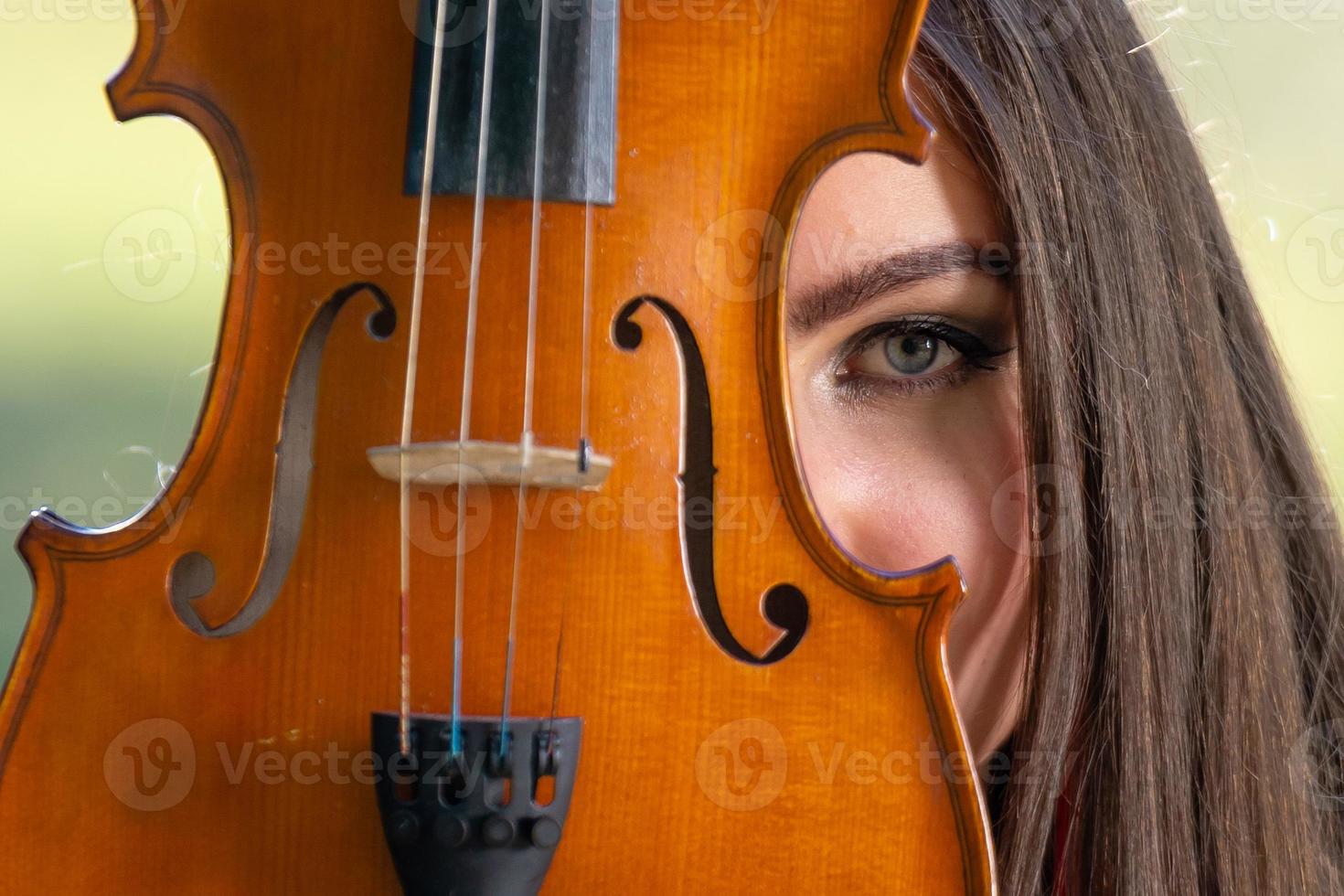 retrato de uma jovem positiva. parte do rosto é coberta pelo pescoço do violino - imagem foto
