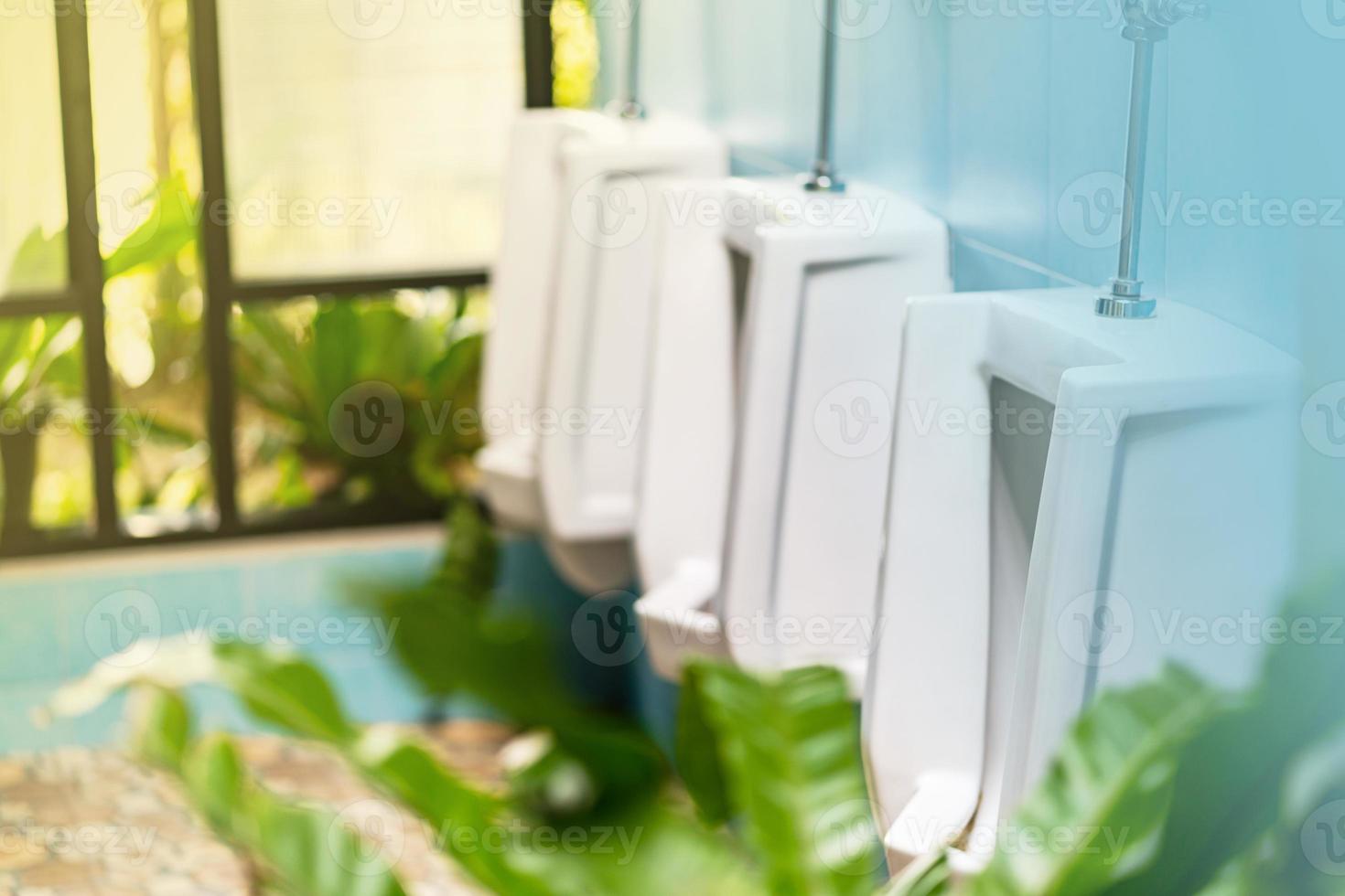 fila de mictórios brancos no banheiro masculino foto