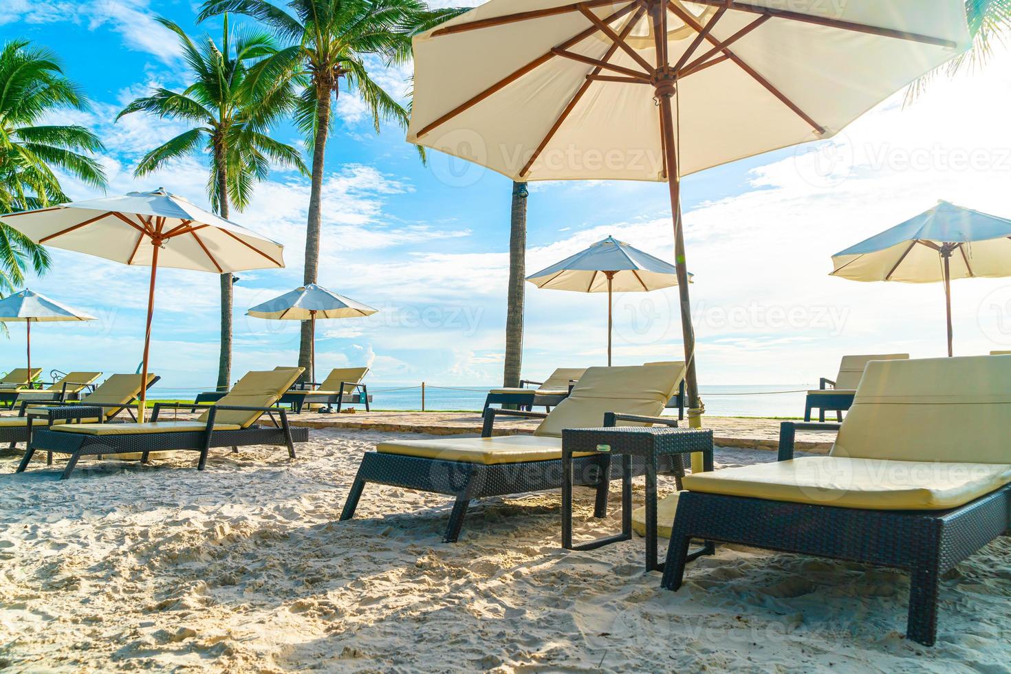 belos guarda-sóis e cadeiras de luxo ao redor de uma piscina ao ar livre em um hotel e resort com coqueiros no céu do pôr do sol ou do nascer do sol - conceito de férias e férias foto