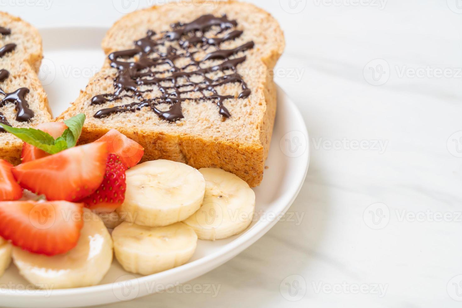 pão integral torrado com banana fresca, morango e chocolate no café da manhã foto