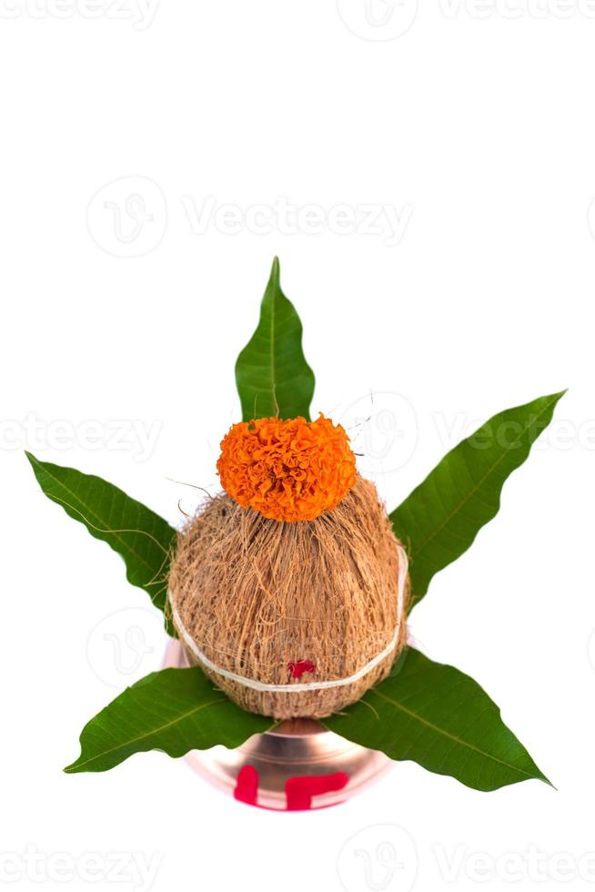 kalash de cobre com coco e folha de manga com decoração floral em fundo branco. essencial no puja hindu. foto