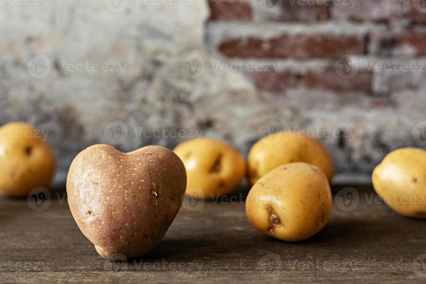 Batata vermelha em forma de coração entre batatas brancas polvilhadas no fundo vintage foto