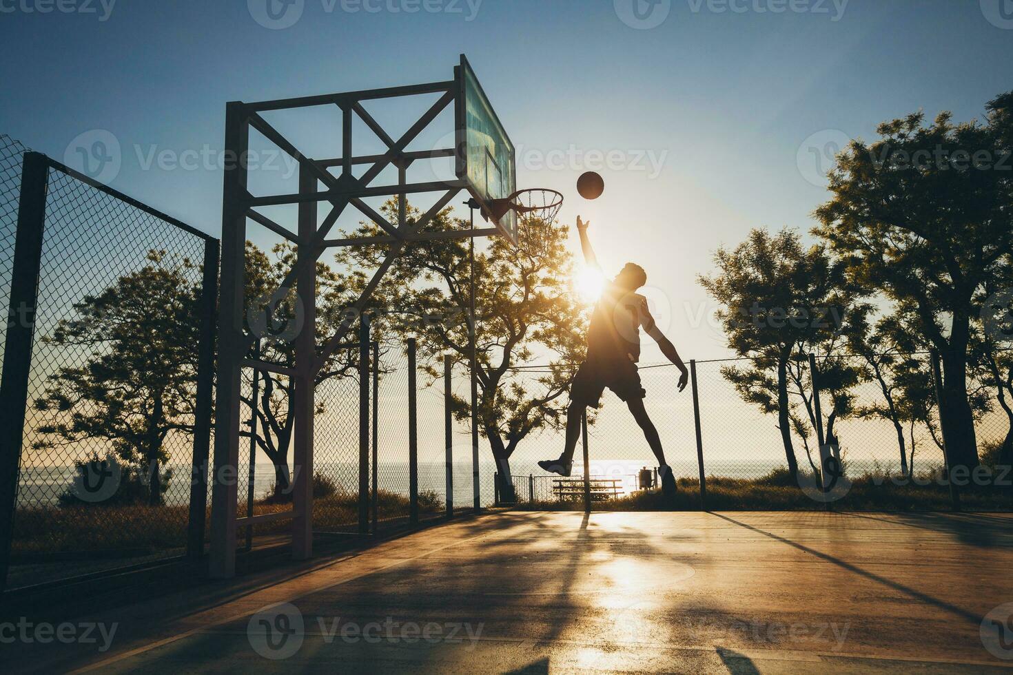 Preto homem fazendo Esportes, jogando basquetebol em nascer do sol, pulando silhueta foto