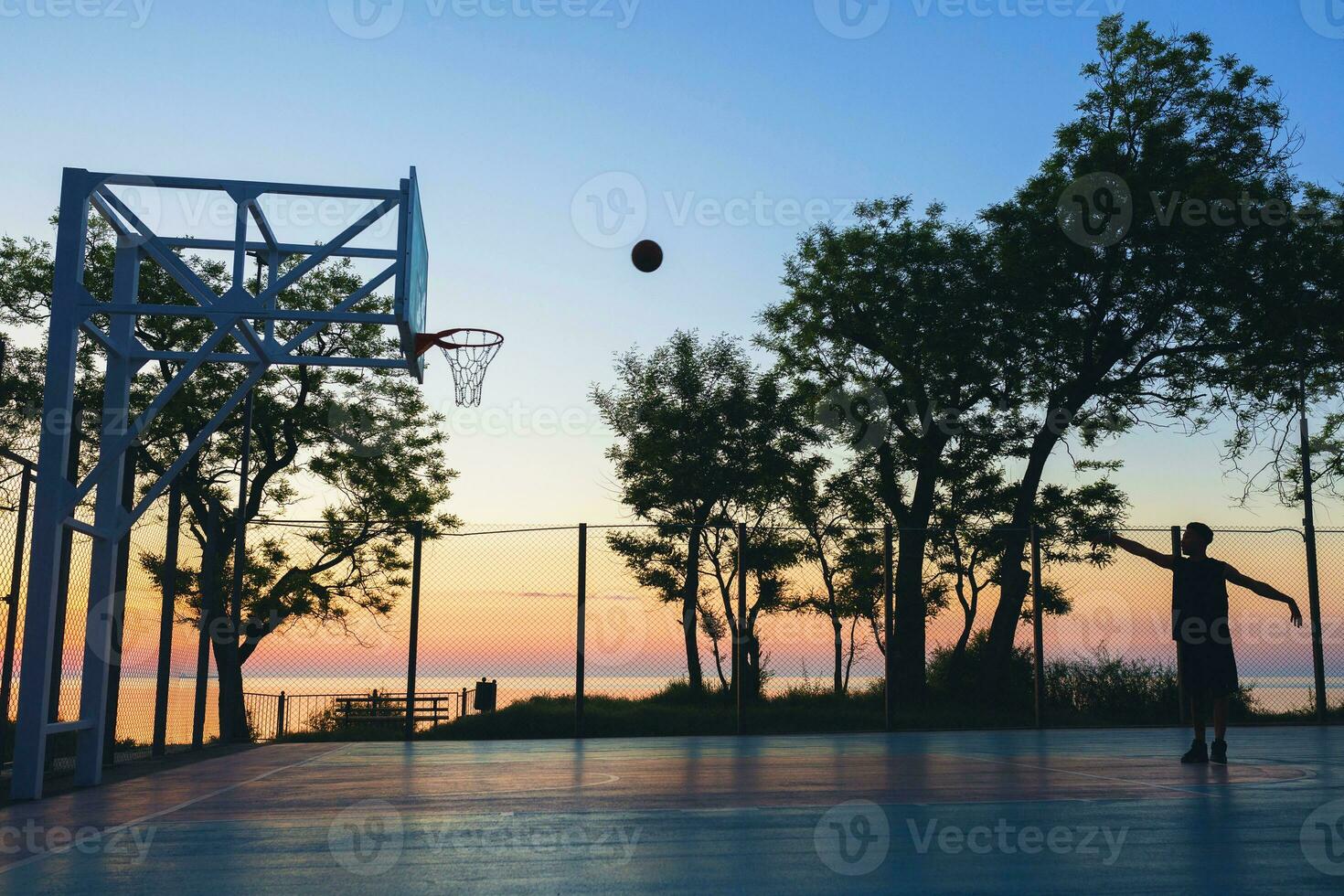 Preto homem fazendo Esportes, jogando basquetebol em nascer do sol, silhueta foto