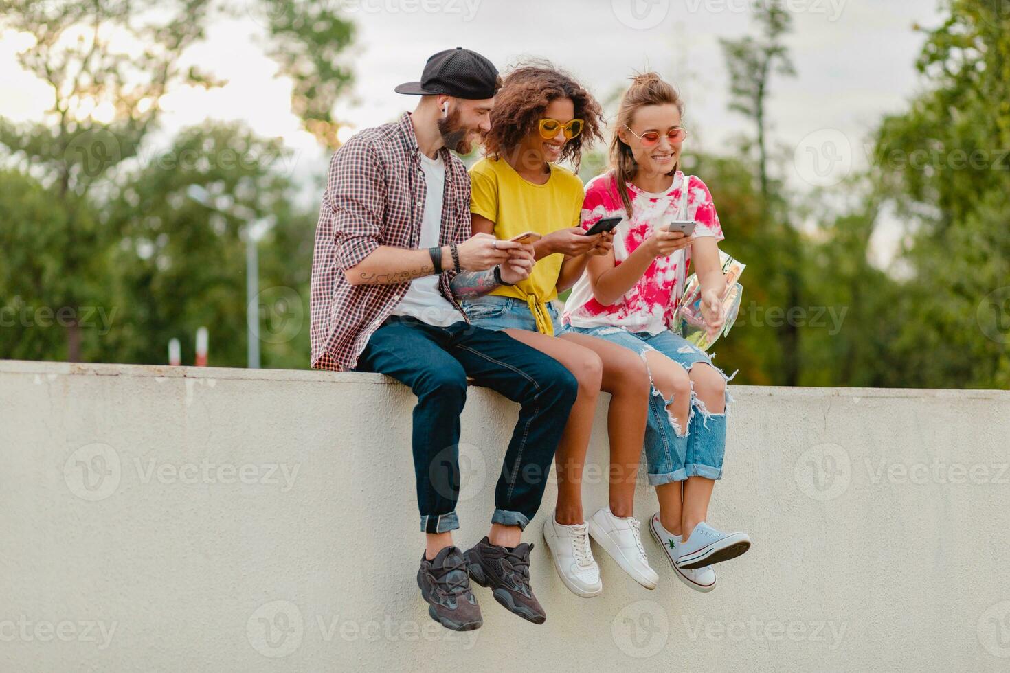 feliz jovem companhia do sorridente amigos sentado dentro parque foto