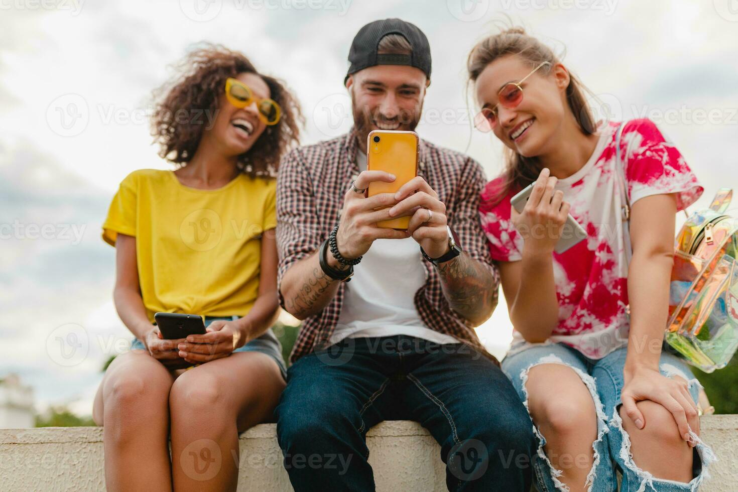 feliz jovem companhia do sorridente amigos sentado dentro parque foto