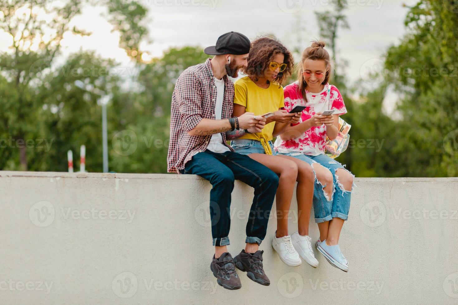 feliz jovem companhia do sorridente amigos sentado dentro parque foto