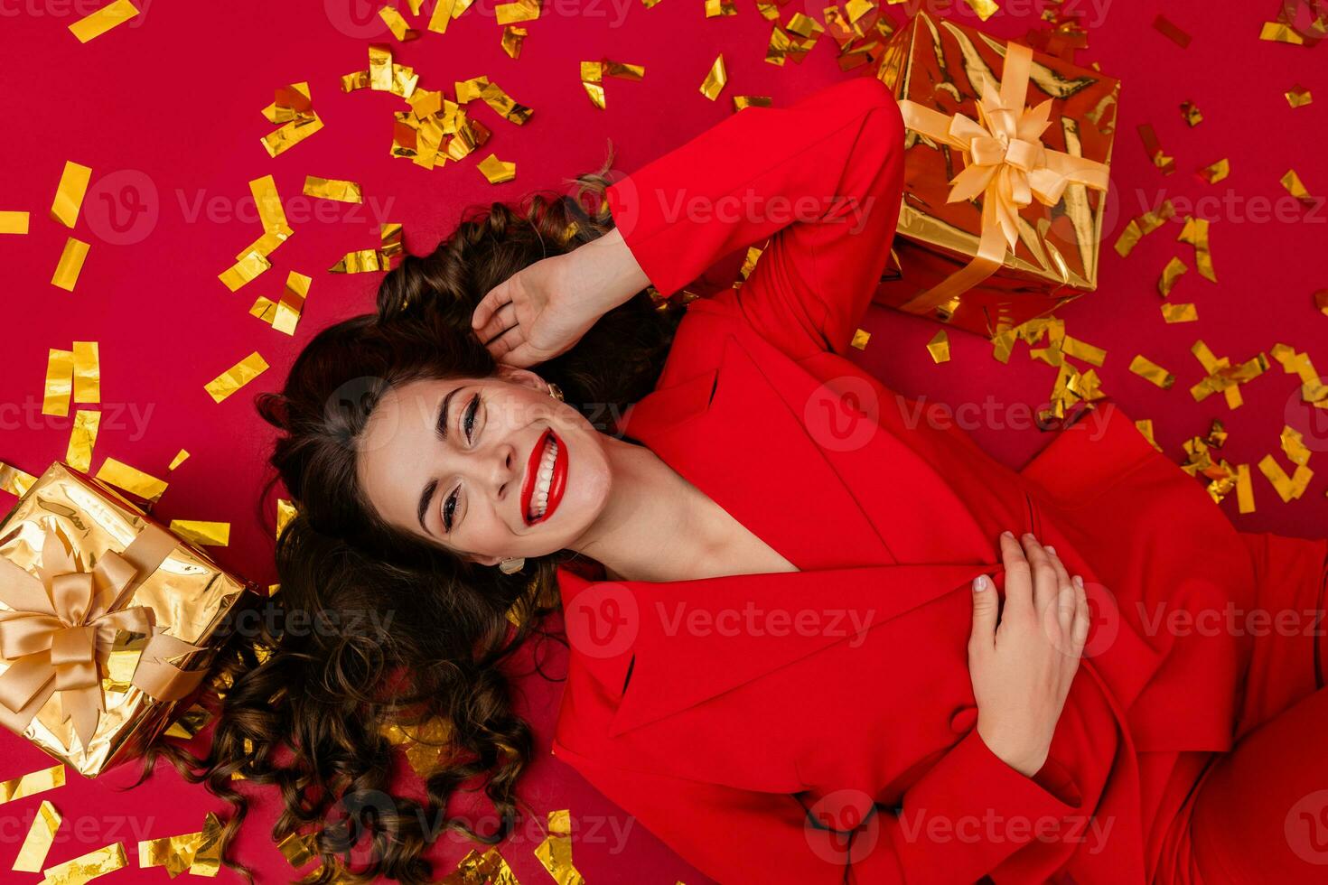 atraente mulher a comemorar Natal em vermelho fundo dentro confete foto