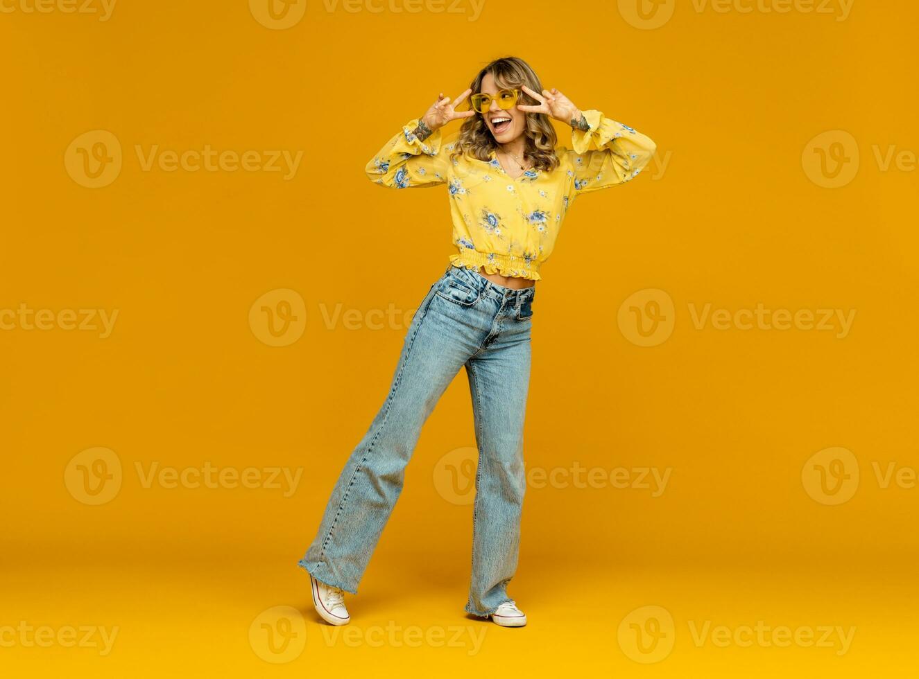 à moda feliz sorridente loiro mulher posando dentro jeans em amarelo fundo foto