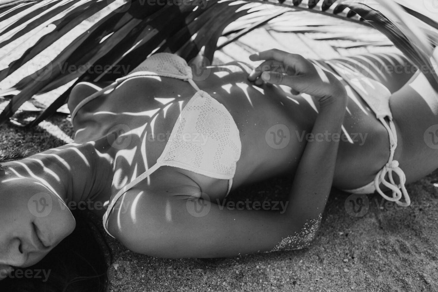 jovem magro mulher dentro branco bikini roupa de banho segurando folha do Palma árvore foto