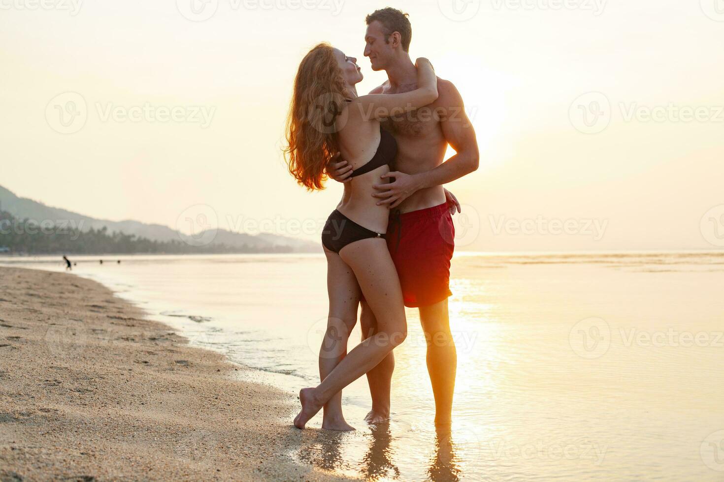 jovem sexy romântico casal dentro amor feliz em verão de praia juntos tendo Diversão vestindo nadar ternos foto