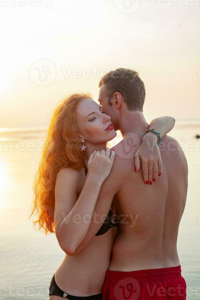 jovem sexy romântico casal dentro amor feliz em verão de praia juntos tendo Diversão vestindo nadar ternos foto