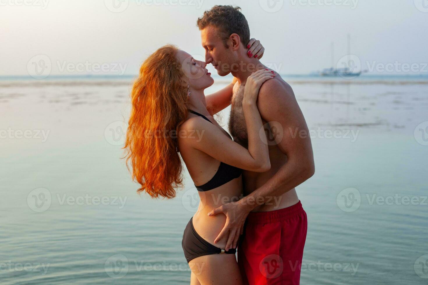 jovem sexy romântico casal dentro amor feliz em verão de praia juntos tendo Diversão vestindo nadar ternos foto